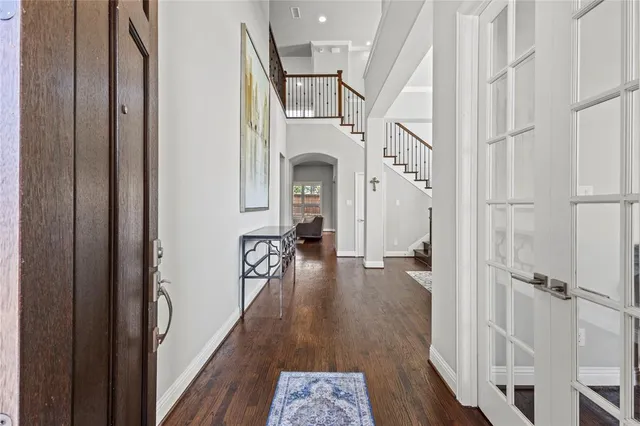 a view of a hallway with wooden floor staircase and living room