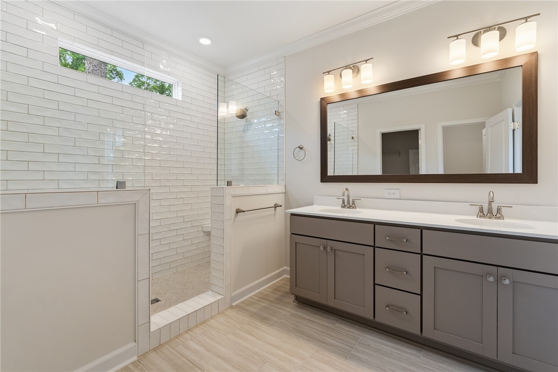 110 Lakeside Drive Anderson, SC 29621 - Photo 21 of 34 This modern bathroom features a spacious shower and a vanity with double sinks, creating a bright and inviting space.