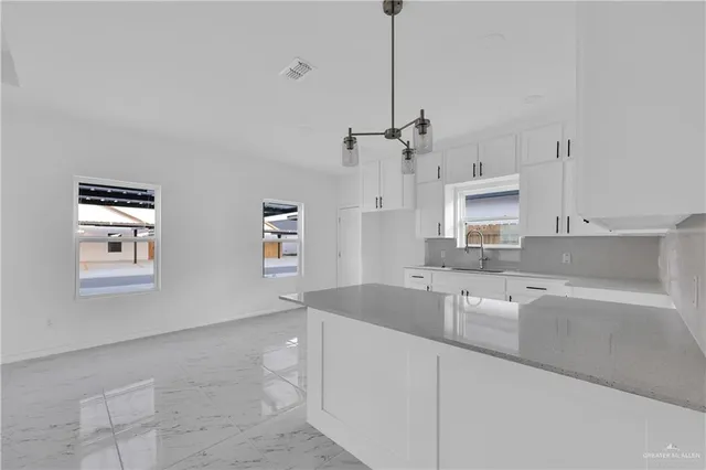 a kitchen with granite countertop a sink a counter space appliances and cabinets