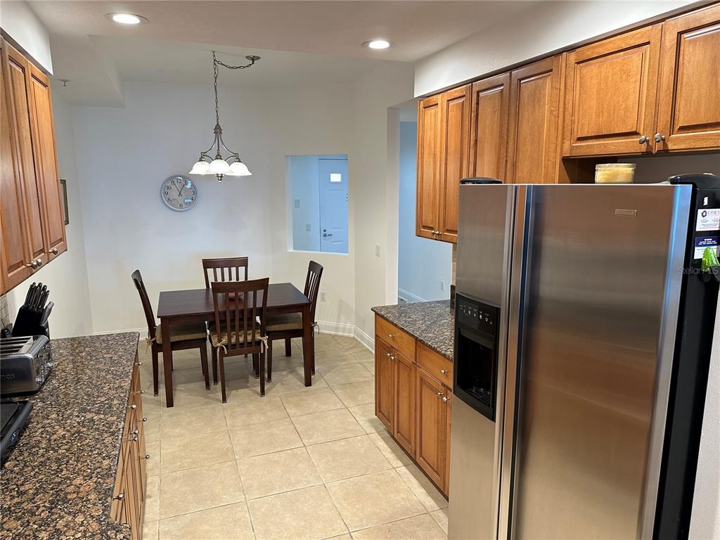 615 Riviera Dunes Way, Unit 406 Palmetto, FL 34221 - Photo 5 of 28 a kitchen with stainless steel appliances granite countertop a refrigerator a stove a sink dishwasher with a dining table and chairs