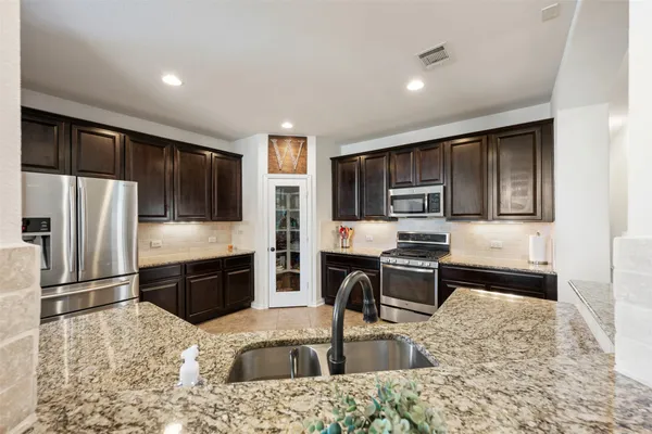 a kitchen with stainless steel appliances granite countertop a refrigerator stove top oven and sink