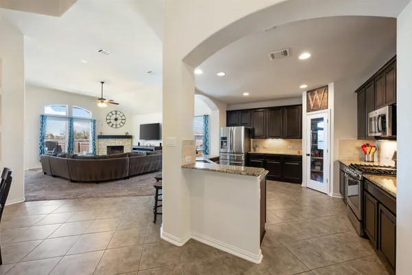 a kitchen with stainless steel appliances kitchen island granite countertop a stove top oven a sink a dining table and chairs