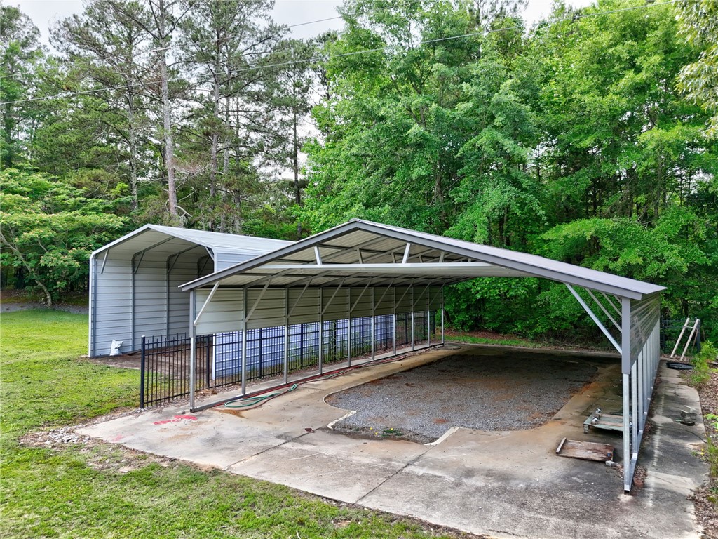 1016 Campbell Road Belton, SC 29627 - Photo 45 of 50 Secure, covered parking and storage solutions complement this property, set against a verdant backdrop.