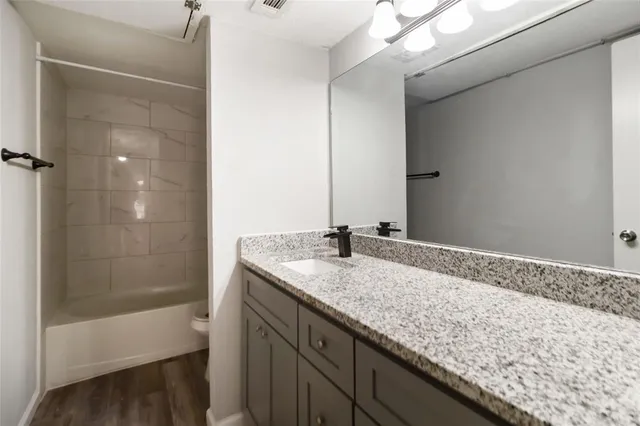 a bathroom with a granite countertop sink and a bathtub