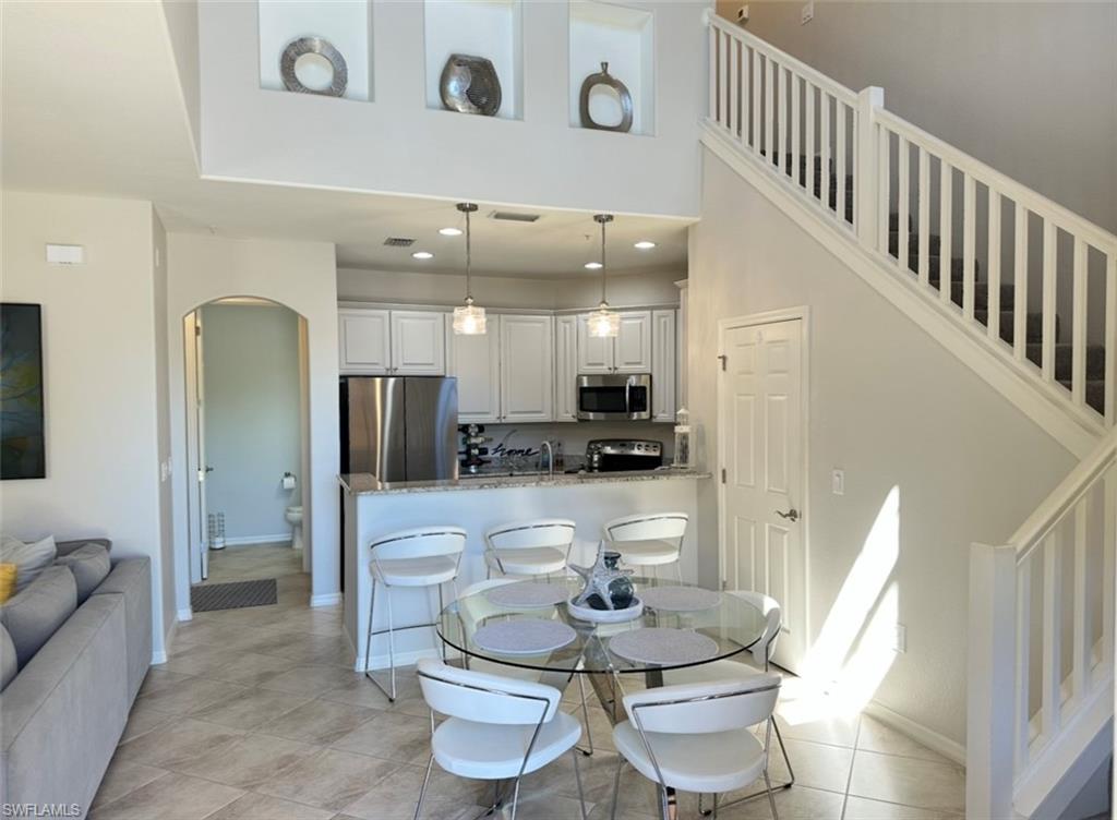 8997 Cambria Circle, Unit 2001 Naples, FL 34113 - Photo 3 of 42 Dining space featuring stairway, recessed lighting, light tile patterned flooring, arched walkways, and a towering ceiling