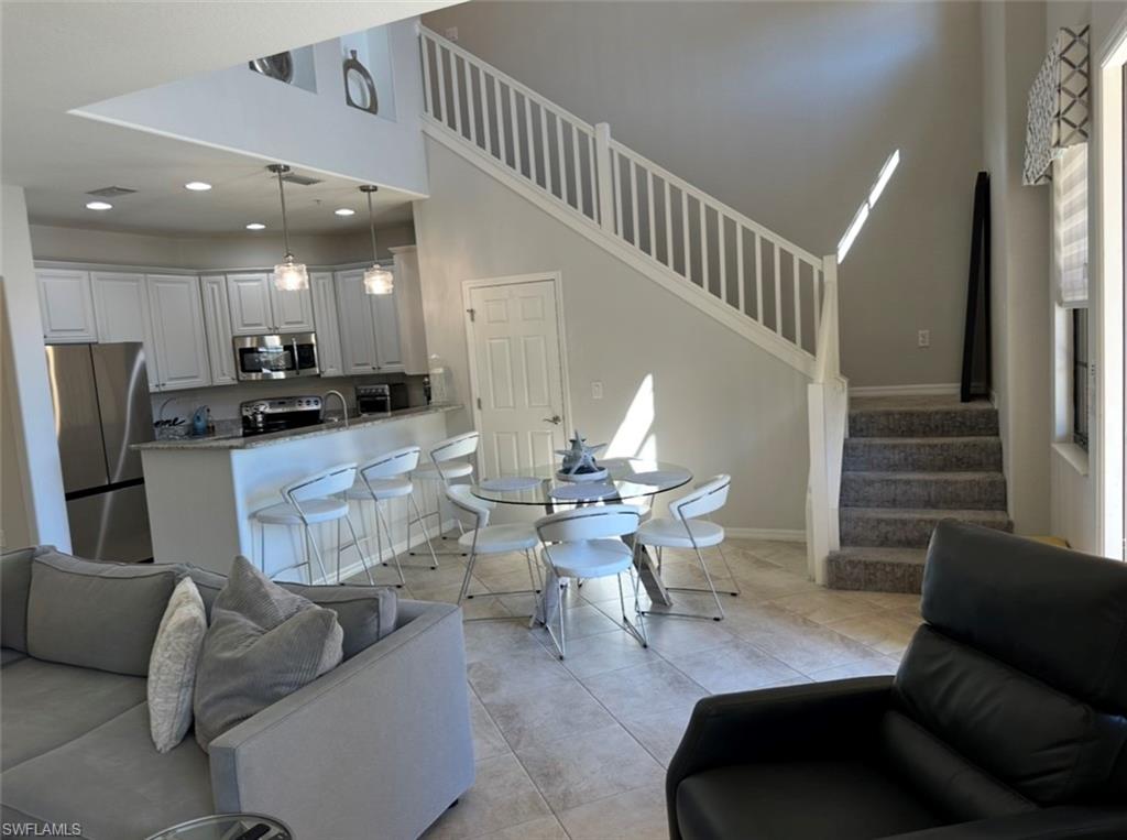 8997 Cambria Circle, Unit 2001 Naples, FL 34113 - Photo 8 of 42 Living room with stairs, recessed lighting, light tile patterned floors, baseboards, and a high ceiling