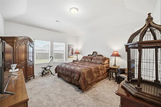 a spacious bedroom with a bed and a dresser next to a window