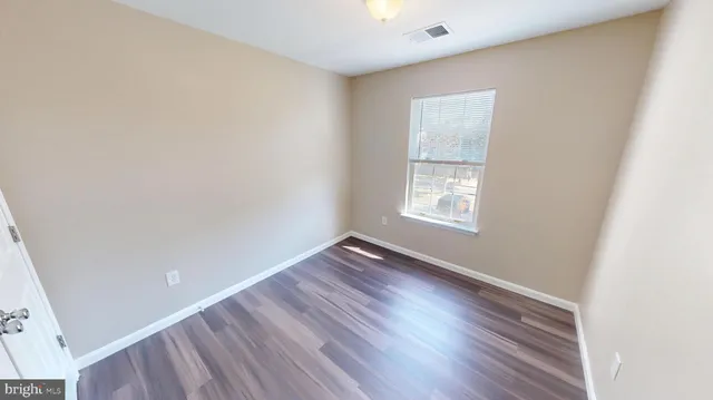 an empty room with wooden floor and entrance