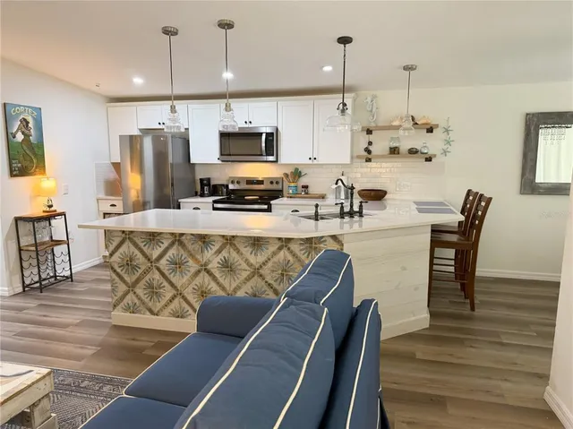 a kitchen with stainless steel appliances kitchen island granite countertop a table chairs microwave and sink