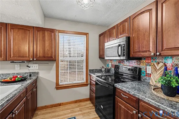 a kitchen with stainless steel appliances granite countertop a stove sink and cabinets
