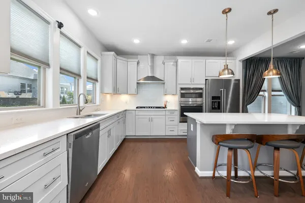 a kitchen with kitchen island a large counter top space a sink stainless steel appliances and cabinets