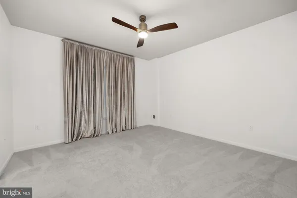 an empty room with a ceiling fan and window