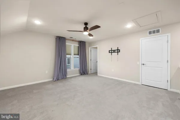 an empty room with chandelier fan and windows