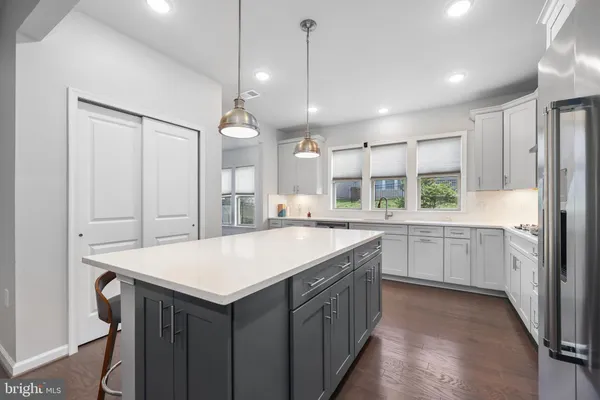 a kitchen with a stove a refrigerator a sink and white cabinets with wooden floor