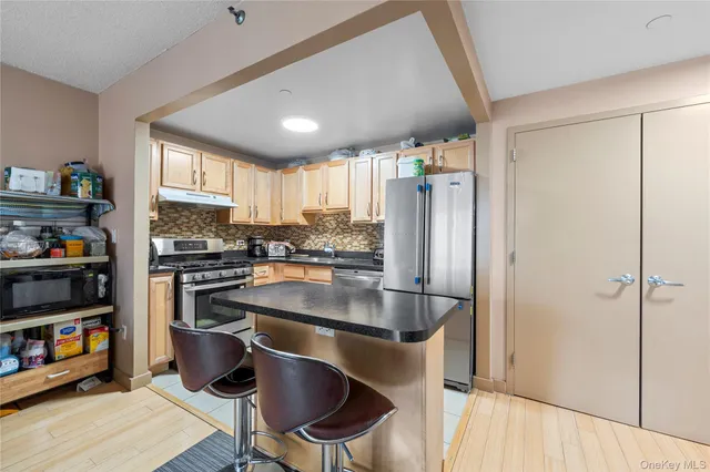 a kitchen with granite countertop a stove a sink and a refrigerator