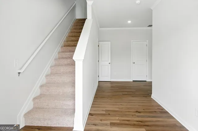 a view of a hallway with wooden floor and staircase