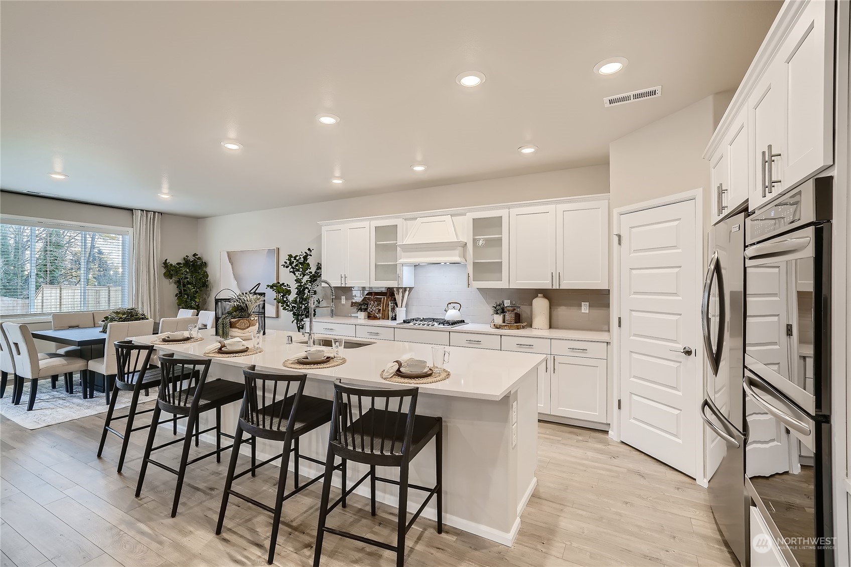 21017 42nd Avenue Southeast, Unit 114 Bothell, WA 98021 - Photo 3 of 22 a kitchen with stainless steel appliances kitchen island granite countertop a dining table chairs stove refrigerator and cabinets