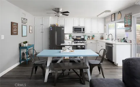 a kitchen with stainless steel appliances a dining table chairs refrigerator and microwave