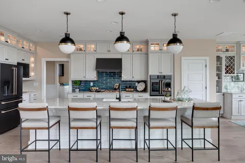 a kitchen with stainless steel appliances kitchen island granite countertop a refrigerator a stove a dining table and chairs with wooden floor