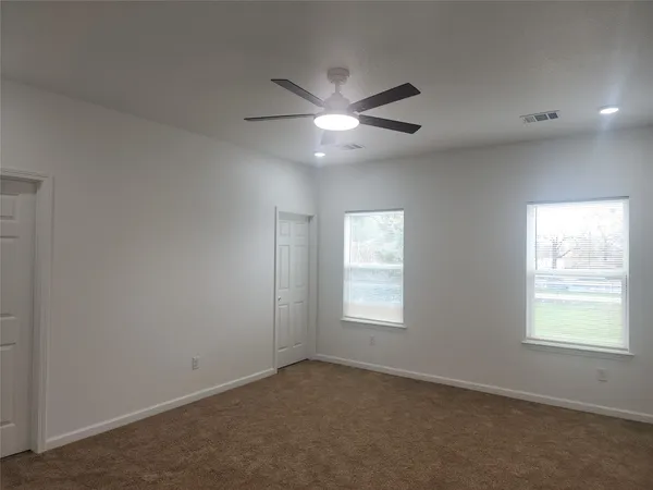en empty room with ceiling fan and window