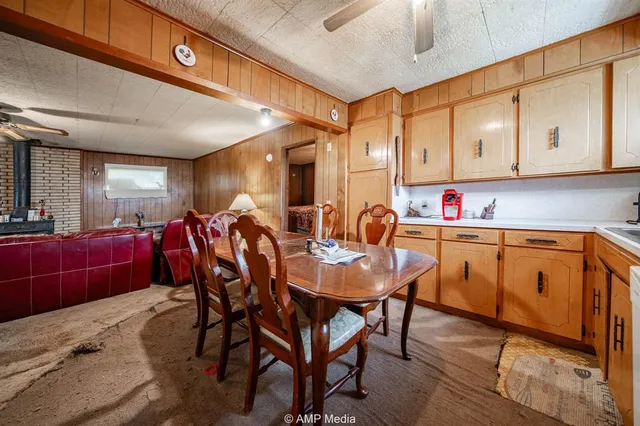 a dining hall with stainless steel appliances kitchen island granite countertop a table chairs sink and cabinets