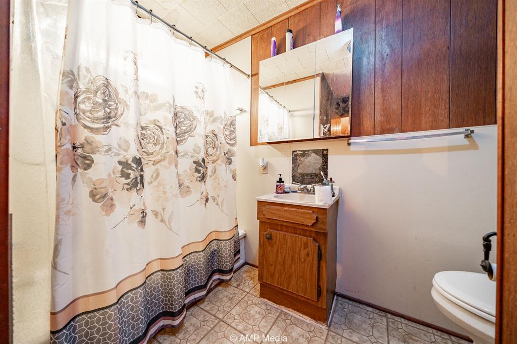 735 Northwest Ave F Hamlin, TX 79520 - Photo 14 of 18 a bathroom with a granite countertop sink and a mirror