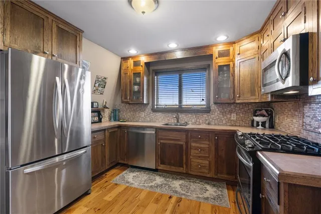 a kitchen with stainless steel appliances granite countertop a refrigerator a sink dishwasher a stove and a refrigerator