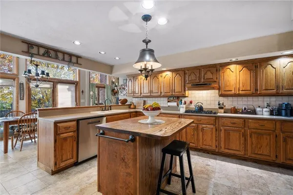 a kitchen with granite countertop a sink a stove and chairs