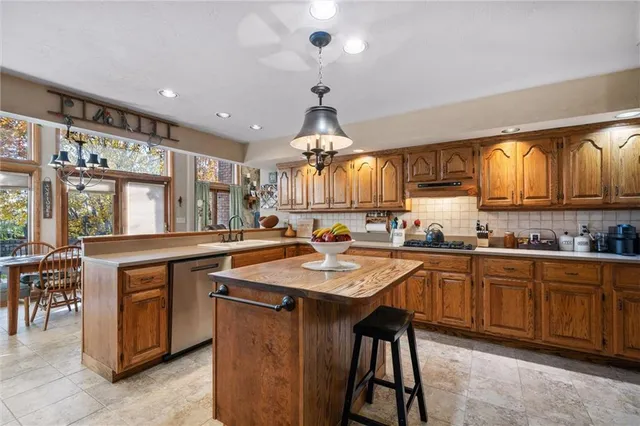 a kitchen with granite countertop a sink a stove and chairs