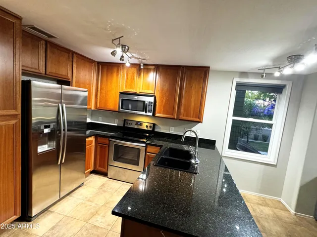 a kitchen with granite countertop a refrigerator and a stove top oven