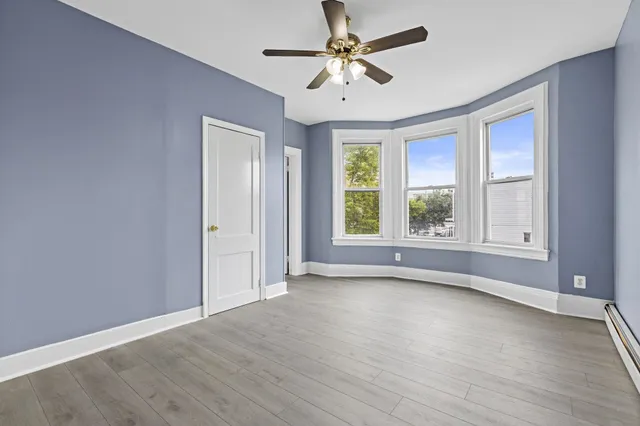 an empty room with wooden floor and windows