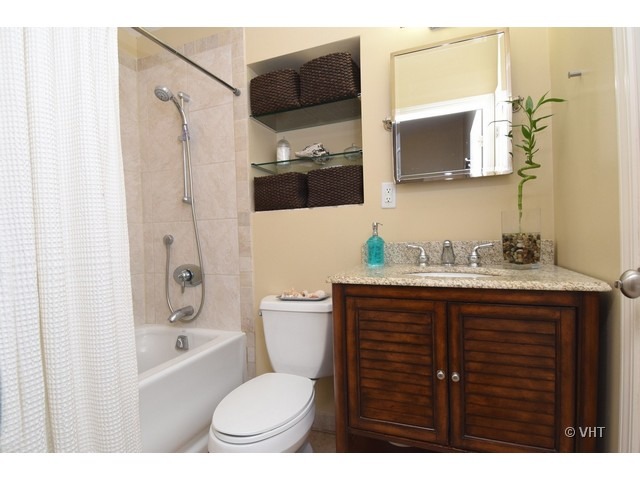 924 Spring Road Elmhurst, IL 60126 - Photo 11 of 18 a bathroom with a granite countertop sink toilet a mirror a bathtub and shower
