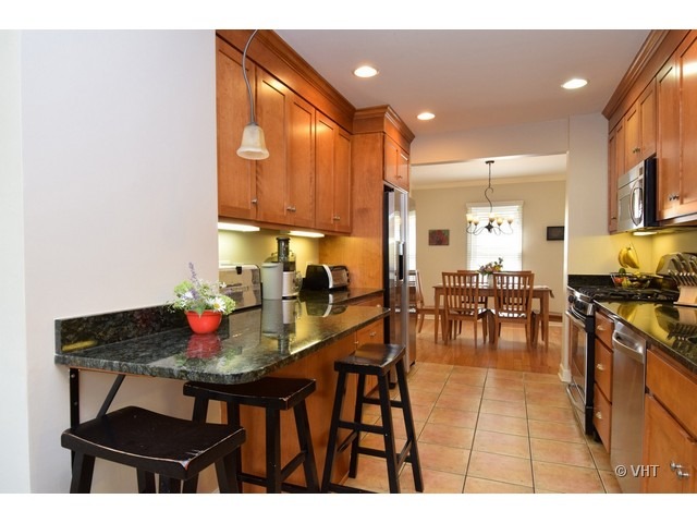 924 Spring Road Elmhurst, IL 60126 - Photo 7 of 18 a kitchen with stainless steel appliances kitchen island granite countertop a dining table chairs and a white refrigerator