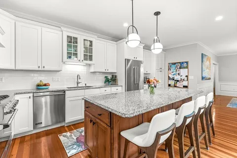 a kitchen with stainless steel appliances granite countertop a kitchen island a table and chairs in it