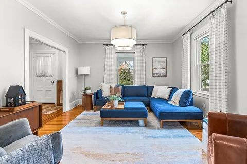 a living room with furniture a large window and a chandelier