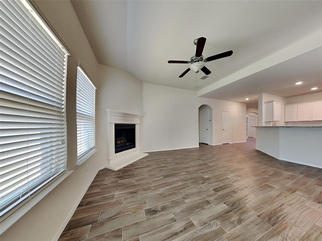 506 Robinson Way Fate, TX 75189 - Photo 2 of 30 Unfurnished living room featuring wood finish floors, a fireplace with raised hearth, arched walkways, ceiling fan, and recessed lighting