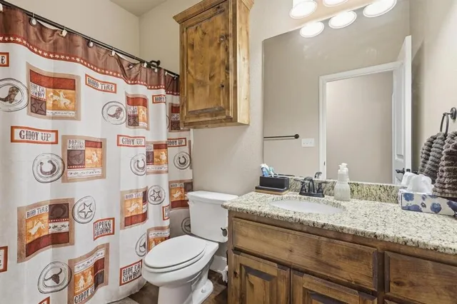 a bathroom with a granite countertop toilet sink and a mirror