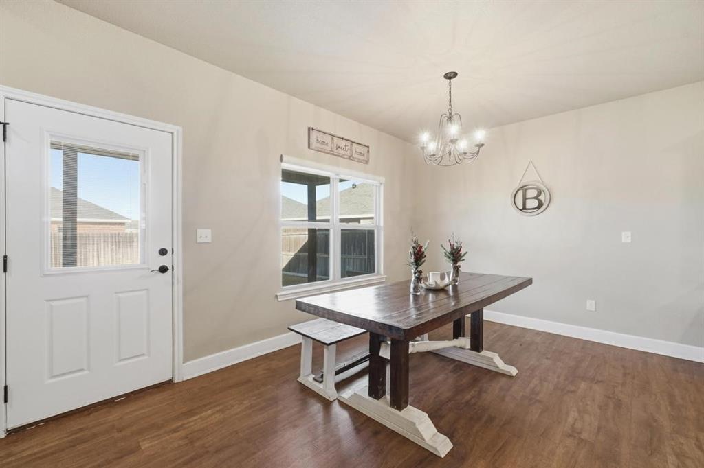 7414 Morning Glory Road Abilene, TX 79602 - Photo 21 of 34 a dining room with wooden floor a chandelier a wooden table and chairs