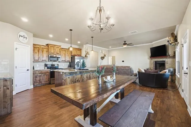 a large living room with stainless steel appliances kitchen island granite countertop a table chairs and a refrigerator