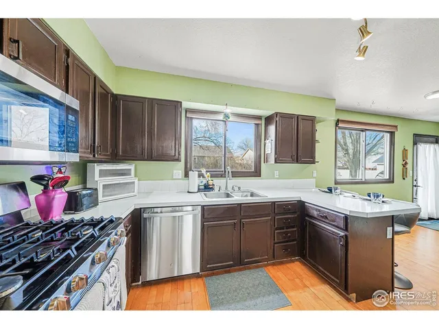 a kitchen with stainless steel appliances granite countertop a stove a sink dishwasher and cabinets with wooden floor