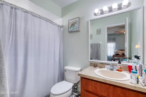a bathroom with a sink a toilet a mirror and shower curtain