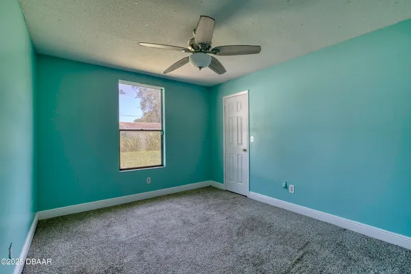 an empty room with a window and a fan