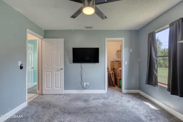 a living room with a flat screen tv and a ceiling fan