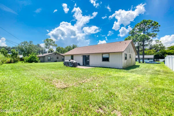 a backyard of a house with table and chairs plants and large tree