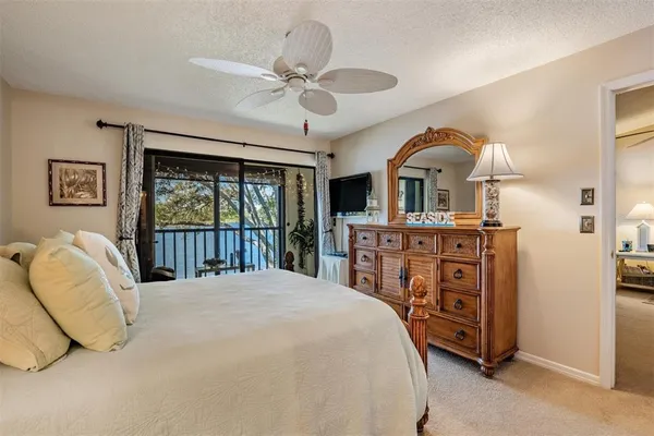 a bedroom with a bed a dresser and large windows