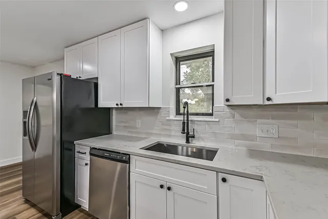 a kitchen with stainless steel appliances granite countertop a sink a refrigerator and cabinets