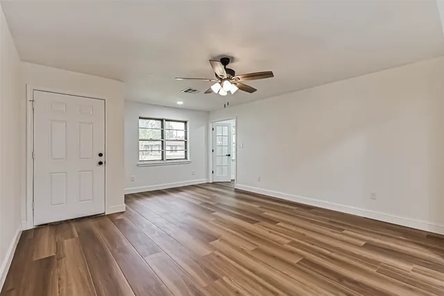 a view of an empty room with window and wooden floor