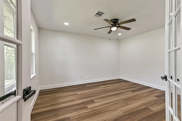 a view of a room with a ceiling fan and hardwood floor