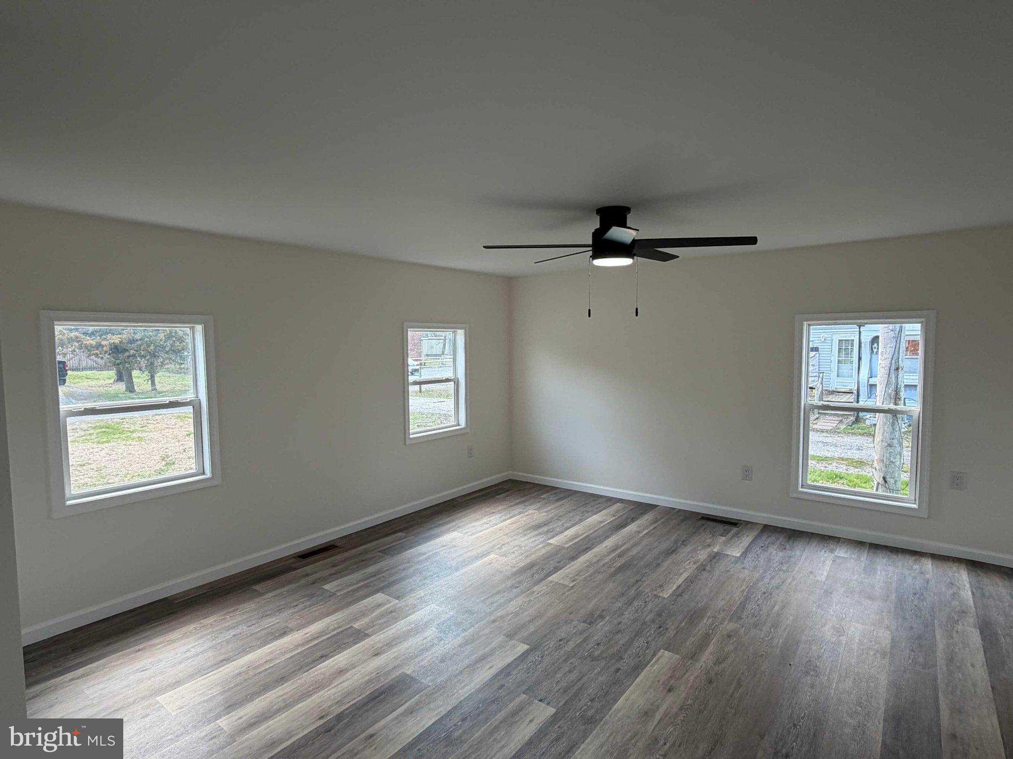 17335 Isdell Road Milford, DE 19963 - Photo 11 of 18 a view of an empty room with a window and wooden floor