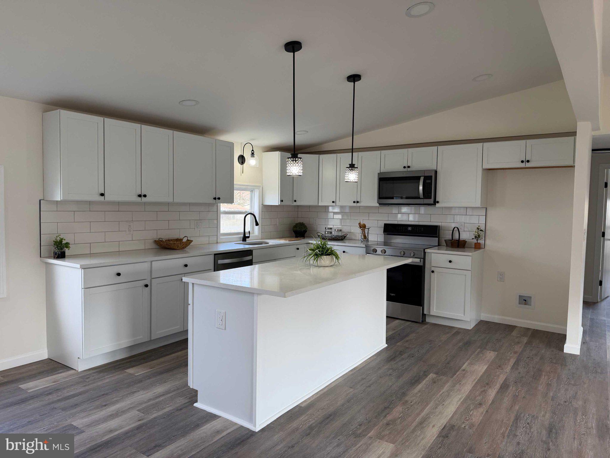 17335 Isdell Road Milford, DE 19963 - Photo 9 of 18 a kitchen with kitchen island white cabinets and white appliances